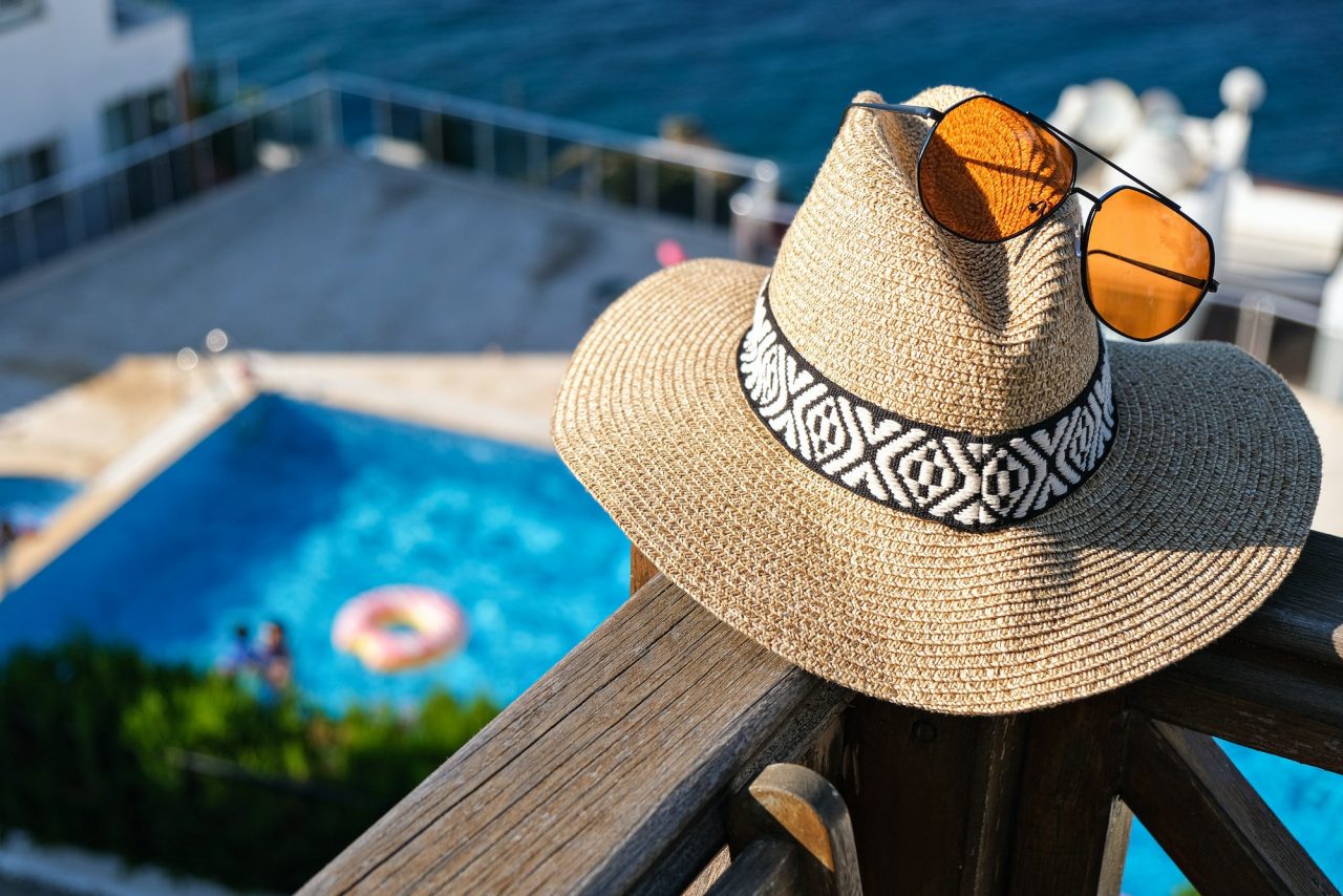 straw-hat-with-sunglasses-wooden-terrace-of-holiday-villa-or-hotel-with-sea-and-wimming-pool-view.jpg